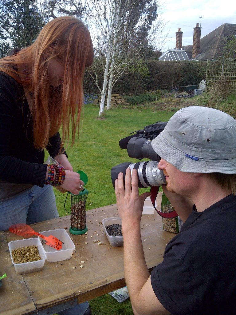 Andrew filming Laura filling up bird feeders